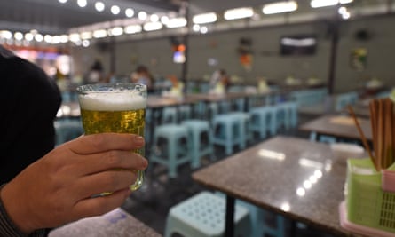 A diner holds a glass of beer at a bar in Hanoi