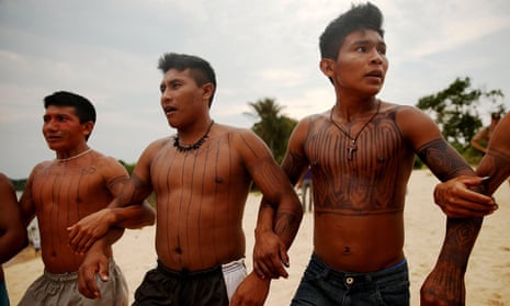 Members of the Munduruku indigenous tribe dance along the Tapajos River during a “Caravan of Resistance’” protest against plans to construct a hydroelectric dam on 27 November 2014 in Sao Luiz do Tapajós, Pará.