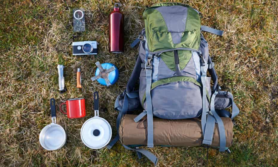 A backpack and camping gear laid out on the grass.