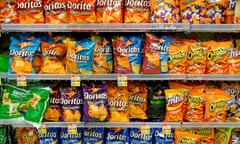 Four grocery-store shelves filled with brightly colored bags of Doritos, mostly in shades of orange.