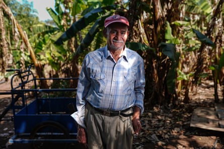 Un hombre se encuentra frente a un fondo frondoso.