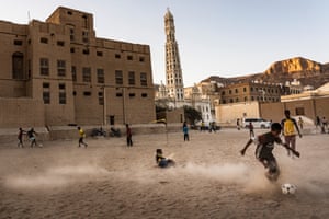 Boys play football at sunset in Tarim, Hadhramaut, Yemen. The minaret of the Al-Mihdar mosque can be seen in the background