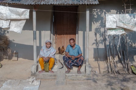 A Bangladeshi man and a woman sitting on the front steps of a house.