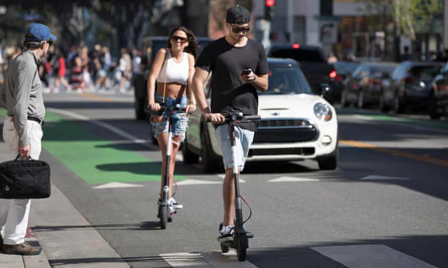 A Bird scooter rider looks at his phone while riding in Santa Monica, California.