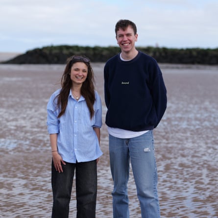 A young woman and man standing on a beach at low tide