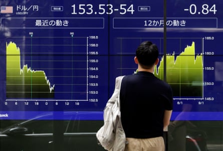 A passerby looks at a large screen of currency rates.