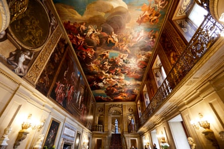 A view from below of the painted hall with murals along the walls and ceilings, and sculptures along the ground floor