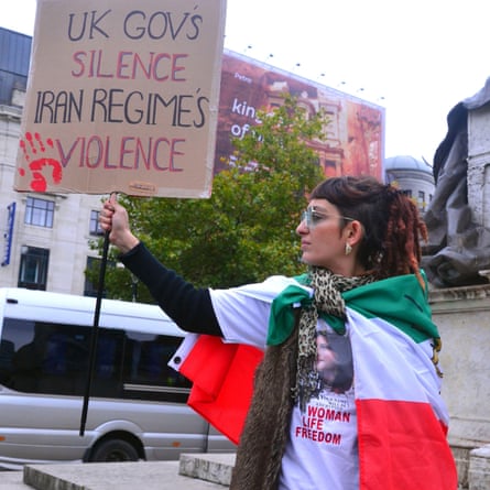 A woman holds a sign reading: ‘UK Gov’s silence Iran regime’s violence’