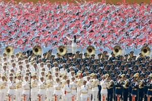 Vast number of people, in different military uniforms, with a person at the centre conducting them