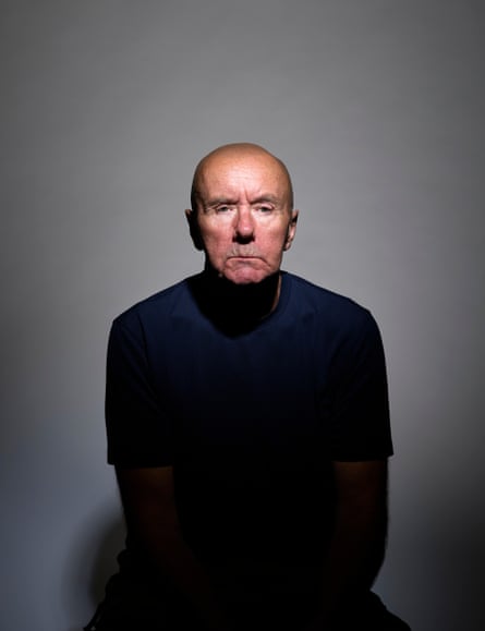A bald-headed man with a dark stop sitting down