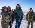 A member of US military personnel gestures while speaking to JD and Usha Vance in a snowy expanse
