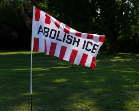 A red and white striped flag with the words 'Abolish ICE' planted on a lawn