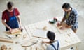 Making wooden detail for interior design<br>Directly above view of busy concentrated carpenters standing at table and making wooden detail for interior design, men drawing outline