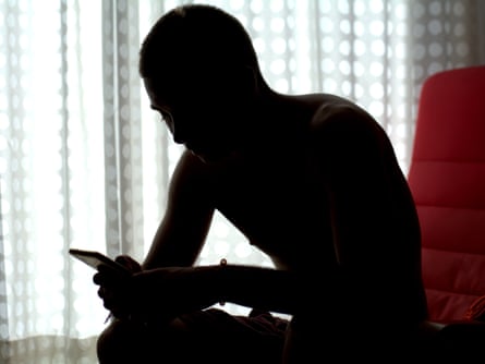 Silhouette of a young man looking at his phone