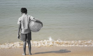 Boy standing with facing sea holding a ball