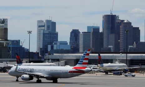 a white blue and red plane on a runway with tall city buildings behind it