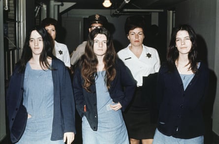Three females wear blue jumpers and sweaters as they walk down a hallway.