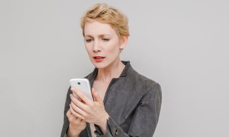 Portrait of distraught blond woman looking at her smartphone in front of grey background
