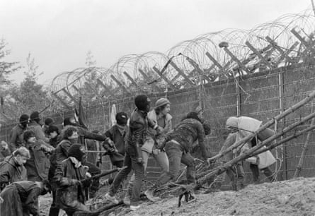 A black and white photo shows protesters scale the fence of a construction site of a nuclear recycling power plant in Wackersdorf, West Germany, 31 March 1986