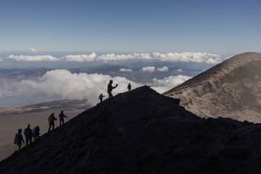 Visitors climb Mount Etna as smoke rises from its volcano
