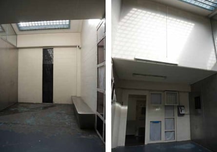 a concrete space with high white walls with a light from above that is obscured by bars. There is a small mental bench and blocked out windows