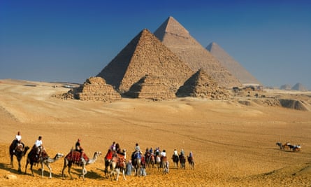 Tourists riding camels near the pyramids of Giza, Cairo