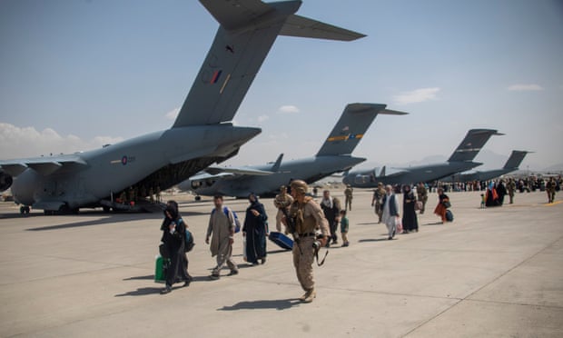 UK soldier leading evacuees to planes for evacuation from Kabul.