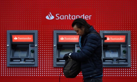 A pedestrian passes ATMs at a Santander bank branch in London