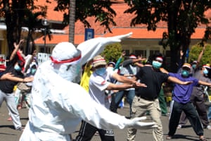 An instructor in protective gear leads coronavirus patients in Indonesia in an aerobics workout.