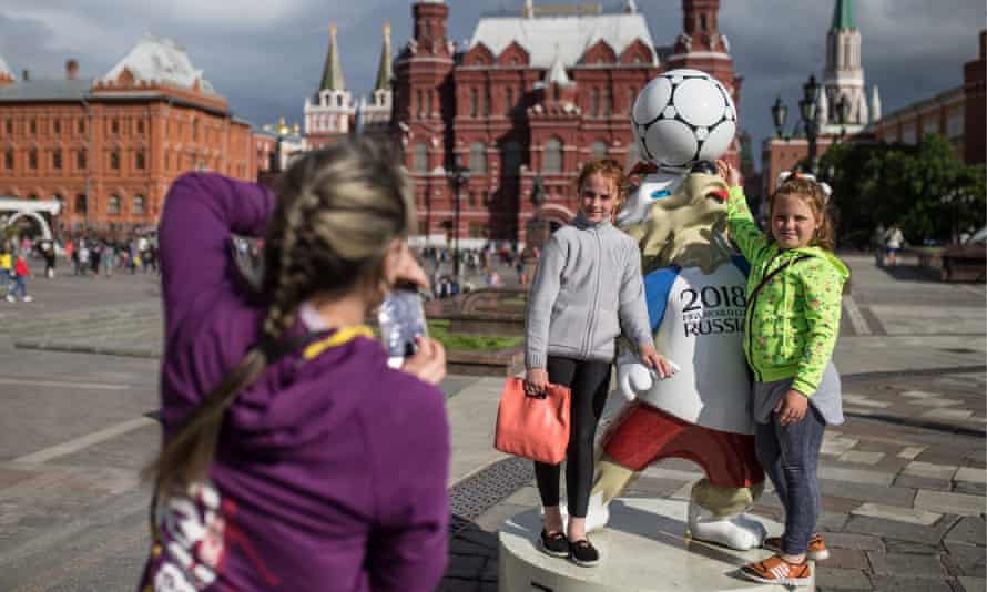 Two girls pose for a photograph by a figure of Wolf Zabivaka, the official mascot of the 2018 World Cup, in Moscow’s Manezhnaya Square