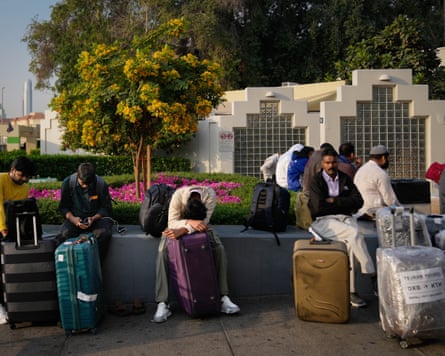 Passengers stranded by the closure of Dubai airport await for assistance in the parking area on Sunday.
