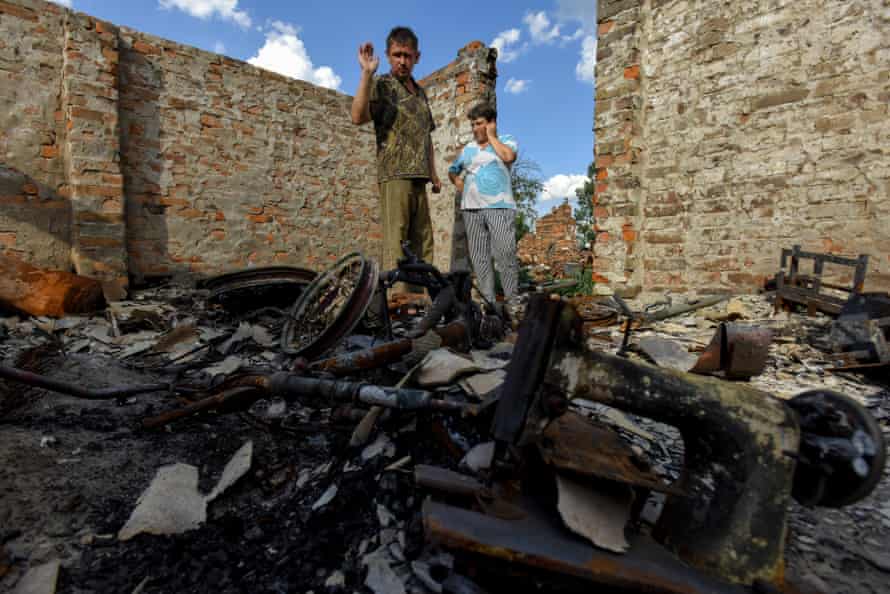 Ihor (left) and Olga (right) stand on the remains of their house in Kukhari village, Kyiv region
