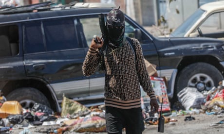 a person holds a gun while walking along a street