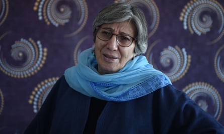 An older south Asian woman with short grey hair and glasses wearing a scarf on her shoulders