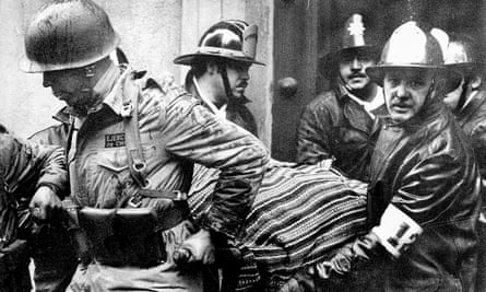 Soldiers and firefighters carry the body of Salvador Allende, wrapped in a Bolivian poncho, out of La Moneda presidential palace after it was bombed during the coup by Gen Augusto Pinochet in Santiago, Chile, 11 September 1973.