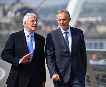 Two men in suits and ties walking across a bridge