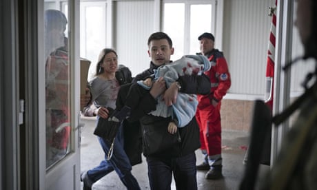 An 18-month-old boy, pictured being rushed into hospital by his parents, was killed by shelling in Mariupol.