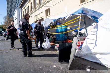 law enforcement stand next to tents along a building