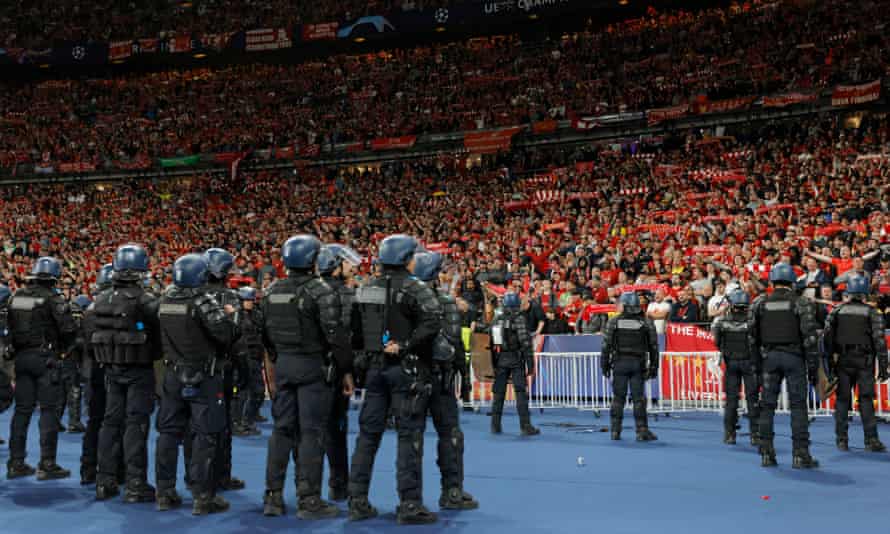 Liverpool fans sing You’ll Never Walk Alone while watched by French riot police.