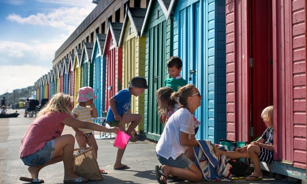 Holidaymakers and beach huts on Boscombe Beach, Bournemouth.