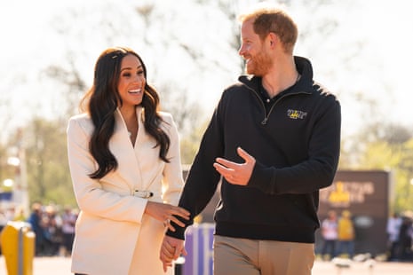 Harry and Meghan walk together holding hands.