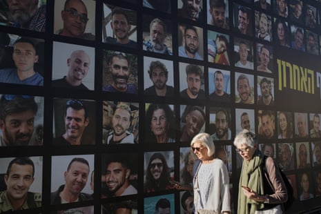 Women walk past a banner in Jerusalem with photographs of hostages who were kidnapped and held by Hamas in the Gaza Strip.