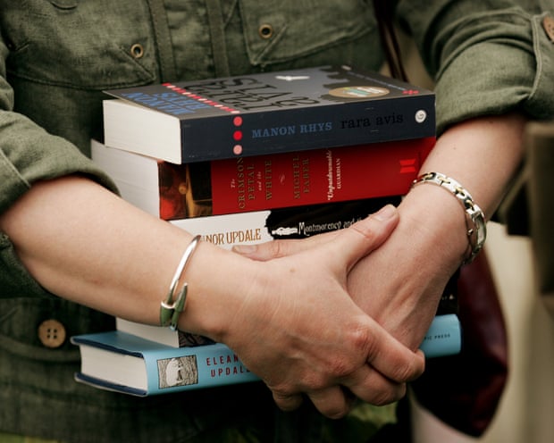 A woman carrying a pile of paperback books