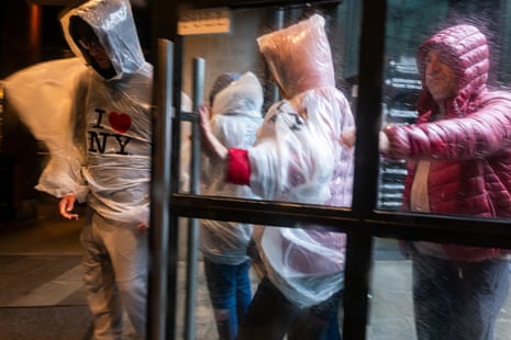 people in ponchos walk in a storm