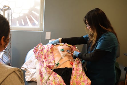 A woman attaches coloured monitor leads to a medical training mannequin's torso
