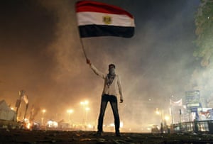 An Egyptian protester waves his national flag as he is surrounded by tear gas fired by riot police in Cairo’s Tahrir Square on 25 January 2013.