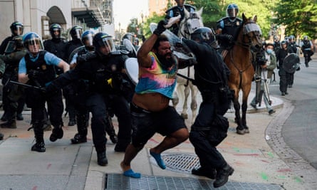 Riot police chase a man as they clear protesters from Lafayette Park in Washington DC.