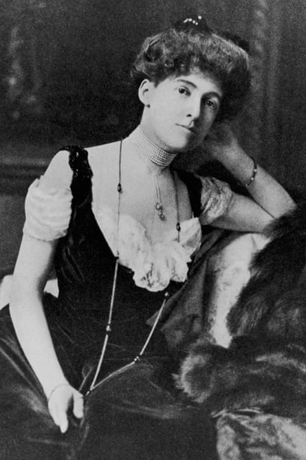 Portrait of American author Edith Wharton (1862-1937) sitting with one arm propped on the back of a sofa, wearing a long necklace