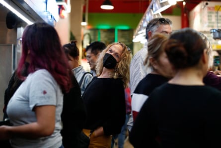 A woman wears a mask in a crowd of people at Grand Central Market in Los Angeles on 3 December.