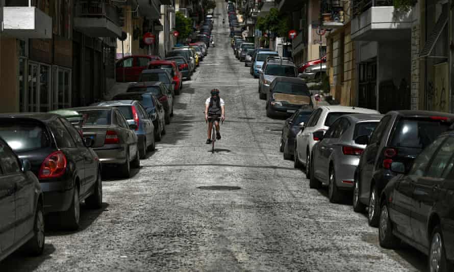 A cyclist rides down a deserted street in central Athens